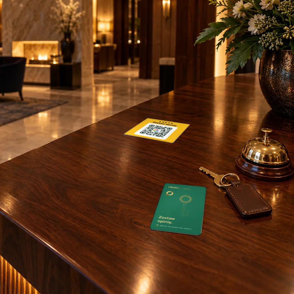 Recepcja hotelu: karta NFC Lokamo na drewnianej ladzie obok dzwonka i klucza, naklejka QR na blacie.